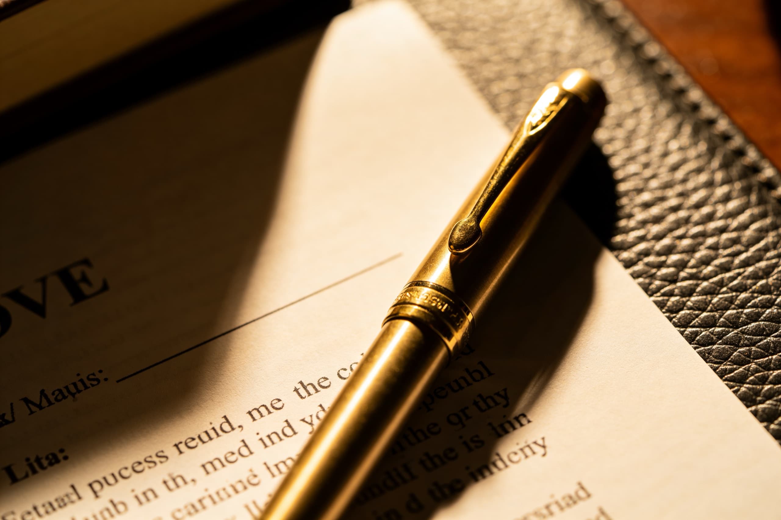 A fountain pen resting on a printed contract on a polished desk