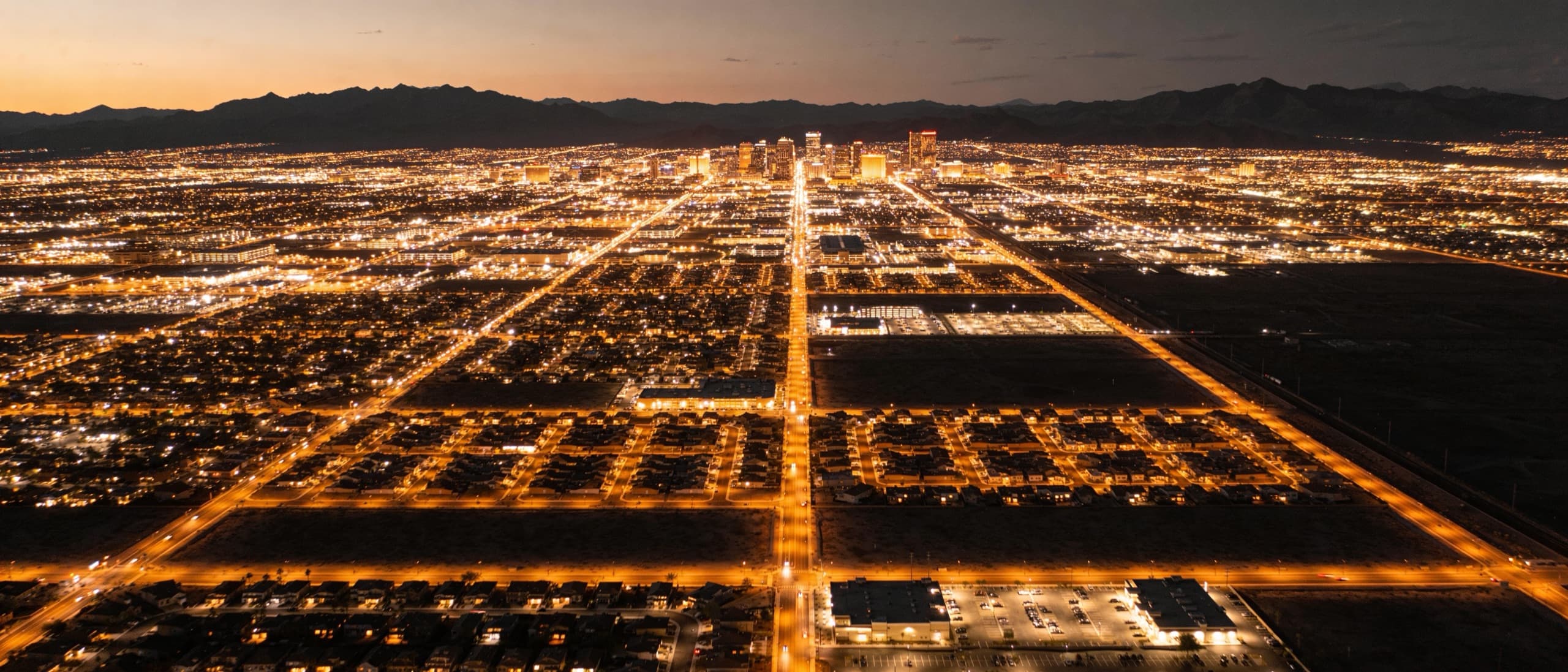 Aerial view of the Phoenix metropolitan valley at warm dusk with mountains on the horizon